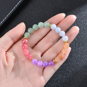 Colorful gemstone bead bracelet with gold spacers held against a black leather background