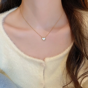 Détail d'un collier doré minimaliste avec un pendentif en nacre en forme de cœur