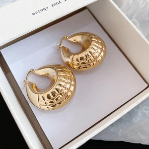 Detailed close-up of gold chunky hoop earrings with quilted pattern texture in a gift box