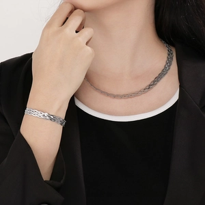 Detalle del conjunto de collar y pulsera de cadena de serpiente tejida en acero titanio