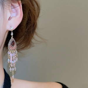 Detail of pink crystal teardrop earrings with long tassels on gold-plated metal base
