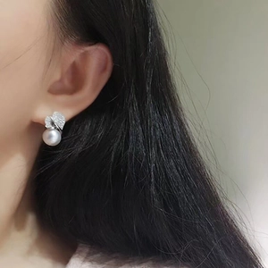 Exquisite leaf-shaped silver earrings with pearl and shimmering diamonds on a model
