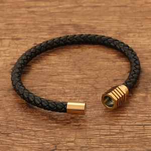 Braided black leather bracelet with golden magnetic stainless steel clasp on wood