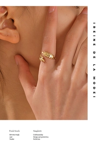 Close-up of elegant gold leaf ring featuring a feather design on a model's finger
