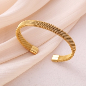 Elegant gold mesh stainless steel open cuff bracelet on soft beige velvet background