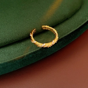 Close-up of a gold-plated twisted ring with clear zircons on green velvet and leather