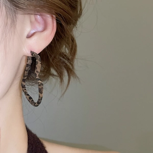 Gros plan de boucles d'oreilles créoles en forme de cœur avec imprimé léopard et texture tissu