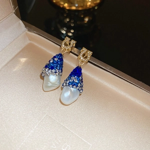 Détail de boucles d'oreilles Gancini de luxe avec cristaux bleus et perles en boîte