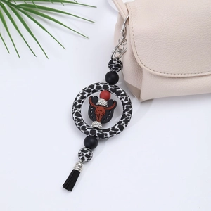 Detail of leopard print ring keychain with bull head pendant, beads and black tassel