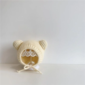 Detailed view of cream knitted baby winter hat with cute bear ears and soft chin straps