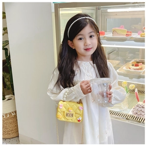 Detail of yellow toddler crossbody bag with pearl handle on child model in cafe