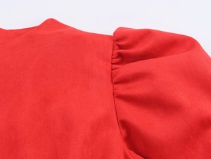 Détail macro d'une robe en daim rouge avec des manches bouffantes et une texture douce