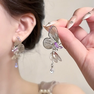 Macro detail of butterfly earrings with purple crystals and silver hollow metal wings