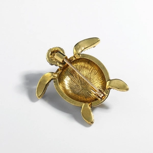 Creative turtle animal brooch with golden finish and pin-back closure on white background
