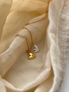 Détail de pendentifs cœur or et argent avec motif d'étoile et zircone sur tissu