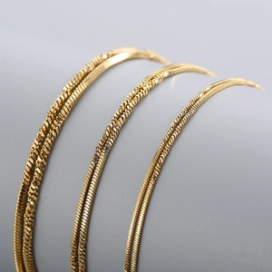 Close-up of golden twisted snake chain necklaces in polished titanium steel