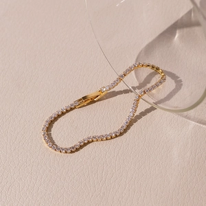 Macro detail of gold-plated tennis bracelet with round-cut zircons on beige leather