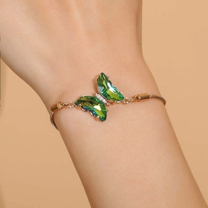 Adjustable gold butterfly bracelet featuring emerald green crystals and sparkling accents