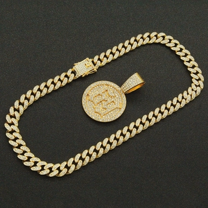 Macro detail of gold paved Cuban chain with iced out round letter pendant necklace