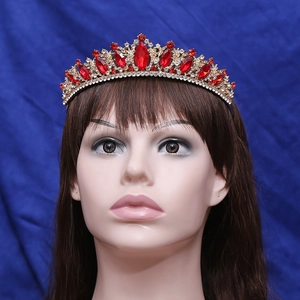 Elegant gold bridal tiara with red gemstones and clear rhinestones on blue fabric