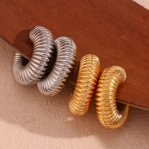 Detail of gold and silver hollow threaded C-shape hoop earrings on dark wood