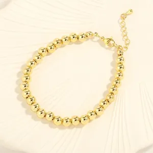Close-up of gold beaded bracelet with lobster clasp, extender chain and teardrop pendant