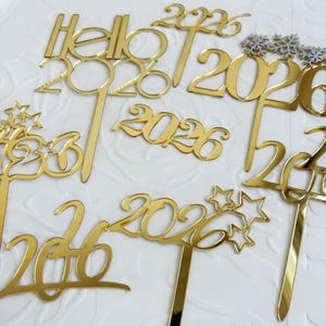 Makroansicht goldener Tortenstecker aus Acryl 2026 mit Sternen und Flocken für Neujahr