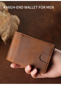Handheld view of a brown vintage crazy horse leather wallet for men on a dark desk