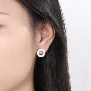 Detail of geometric silver hollow round stud earrings with pave-set zircon on model