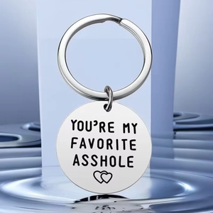 Detailed close-up of engraved stainless steel keychain on a blue reflective surface