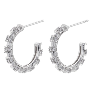 Detailed macro view of silver C-shaped hoop earrings with inlaid cubic zirconia crystals