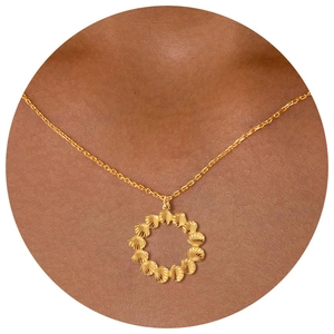 Close-up of a gold round textured shell pendant necklace worn on a female neck