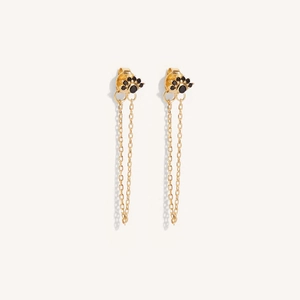 Detail view of gold drop earrings with sunburst stud, black gemstone, and long chain fringe