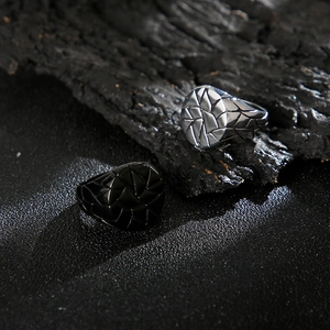 Detail of silver and black textured stainless steel geometric rings for men on dark rock