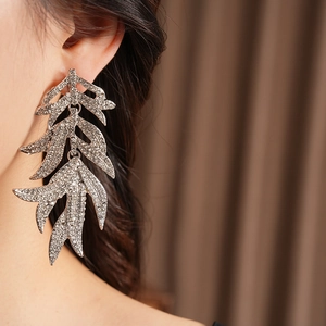 Close-up of vintage silver leaf tassel earrings with rhinestones worn by a model