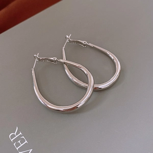 Macro shot of silver-colored oval drop hoop earrings with polished metallic finish