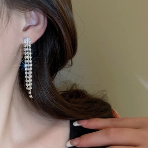 Close-up of sparkling silver tassel earrings with crystal rhinestones on a female model