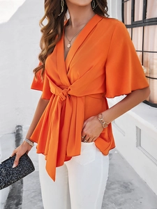 Détail d'un haut orange à col en V avec lien à la taille et ourlet à volants élégant