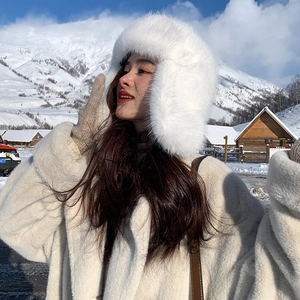Detail of plush faux fur earflap hat and cream coat in snowy mountain scenery