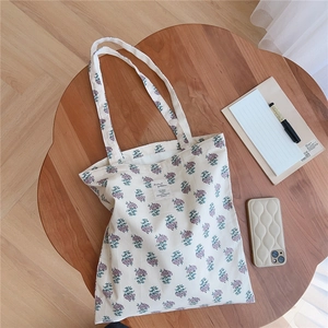 Detailed view of floral canvas tote bag with purple flowers on a wooden desk setup