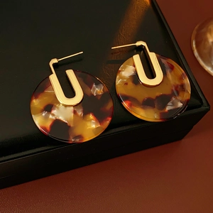 Detailed close-up of tortoise shell resin earrings with gold-plated U-shaped accents