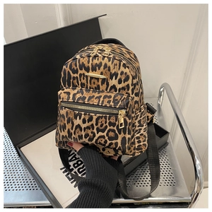 Detail of leopard print oxford backpack featuring golden hardware and front zipper pocket