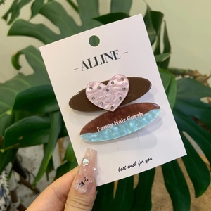 Lot de barrettes coeur strass rose et marbre bleu présentées sur fond de plantes