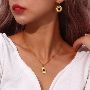 Close-up of golden sunflower pendant necklace and matching earrings set on model