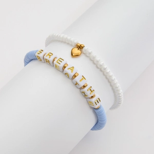 Détail des perles d'argile bleues et des perles de lettres BREATHE avec un pendentif cœur
