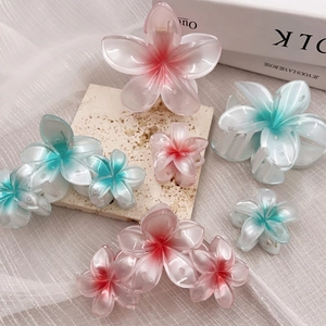 Pink and blue gradient floral hair claws in various sizes on an elegant stone surface