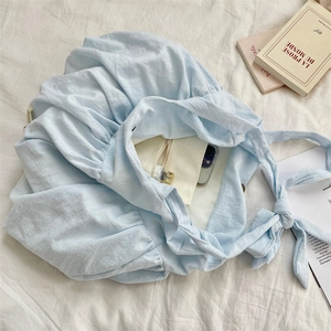 Close-up of light blue pleated canvas tote bag with inner pocket and knotted strap