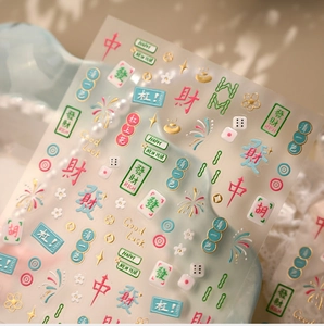 Macro shot of 3D embossed Mahjong nail stickers with gold lucky charms and floral patterns