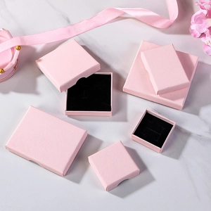 Pink jewelry gift boxes with linen texture and black sponge inserts on marble