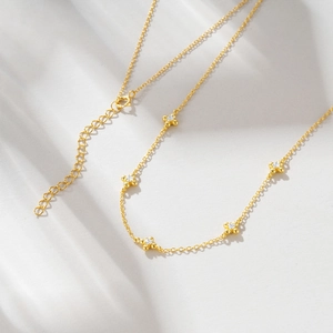 Close-up of a gold 925 silver necklace featuring four clover charms with zircon accents